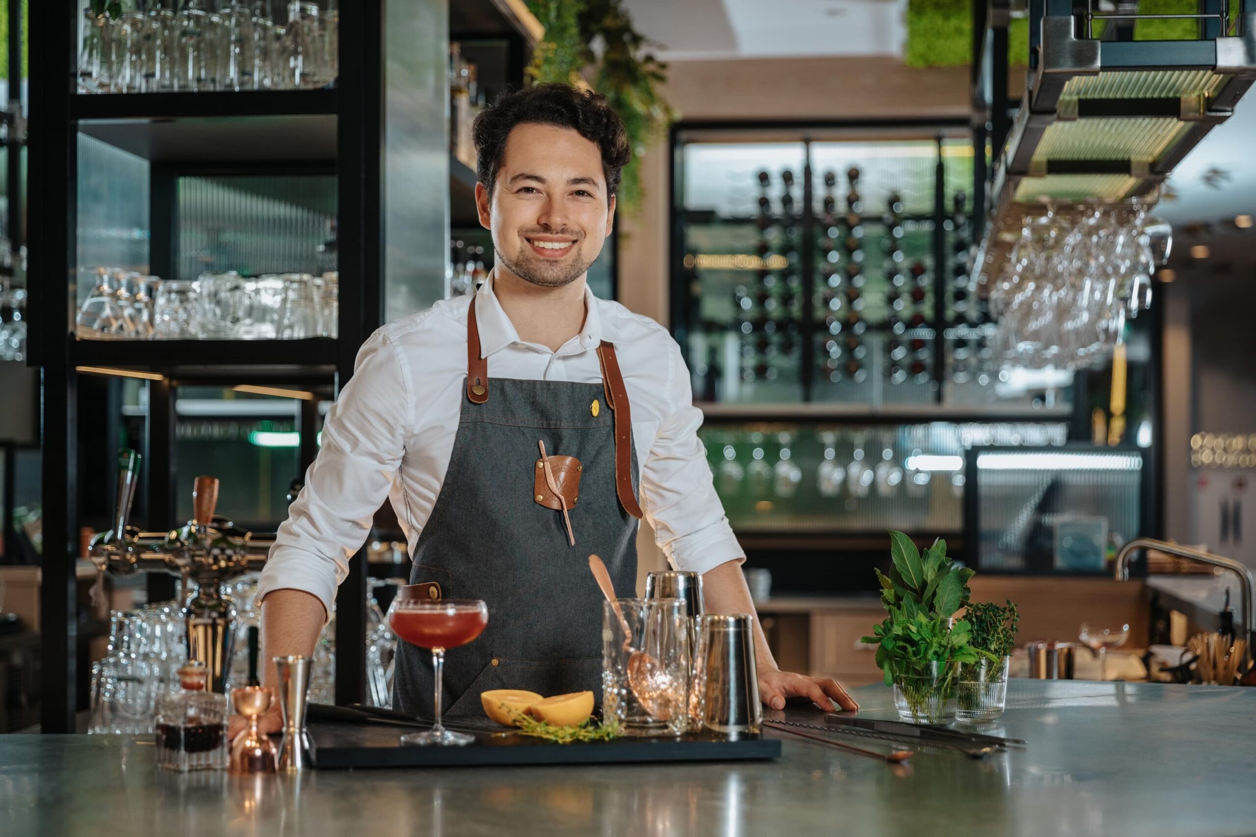 Mixologist crafting a cocktail at the bar counter of botanica wonderbar.