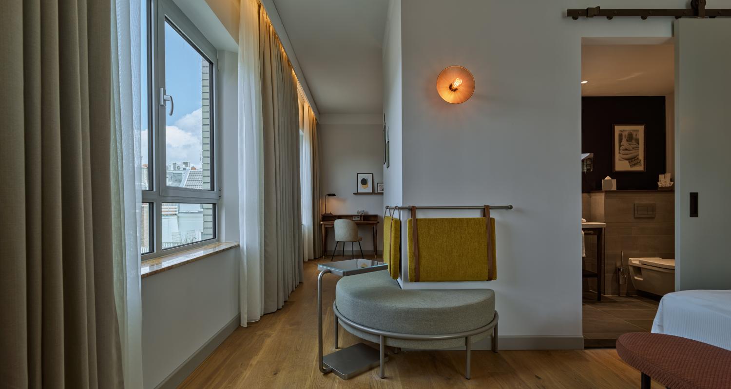 King Suite lounge area with city‑view window and desk at voco The Hague