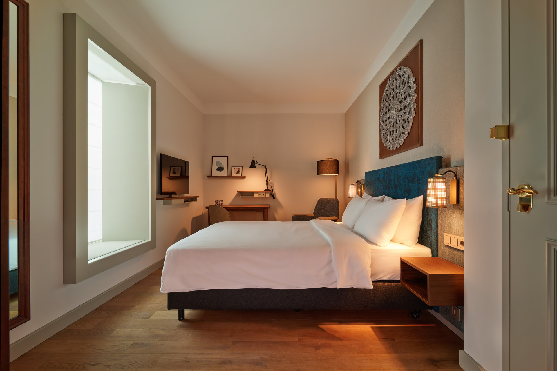 Standard Atrium room at voco The Hague with queen bed, natural daylight, USB charging, and high-quality bedding.