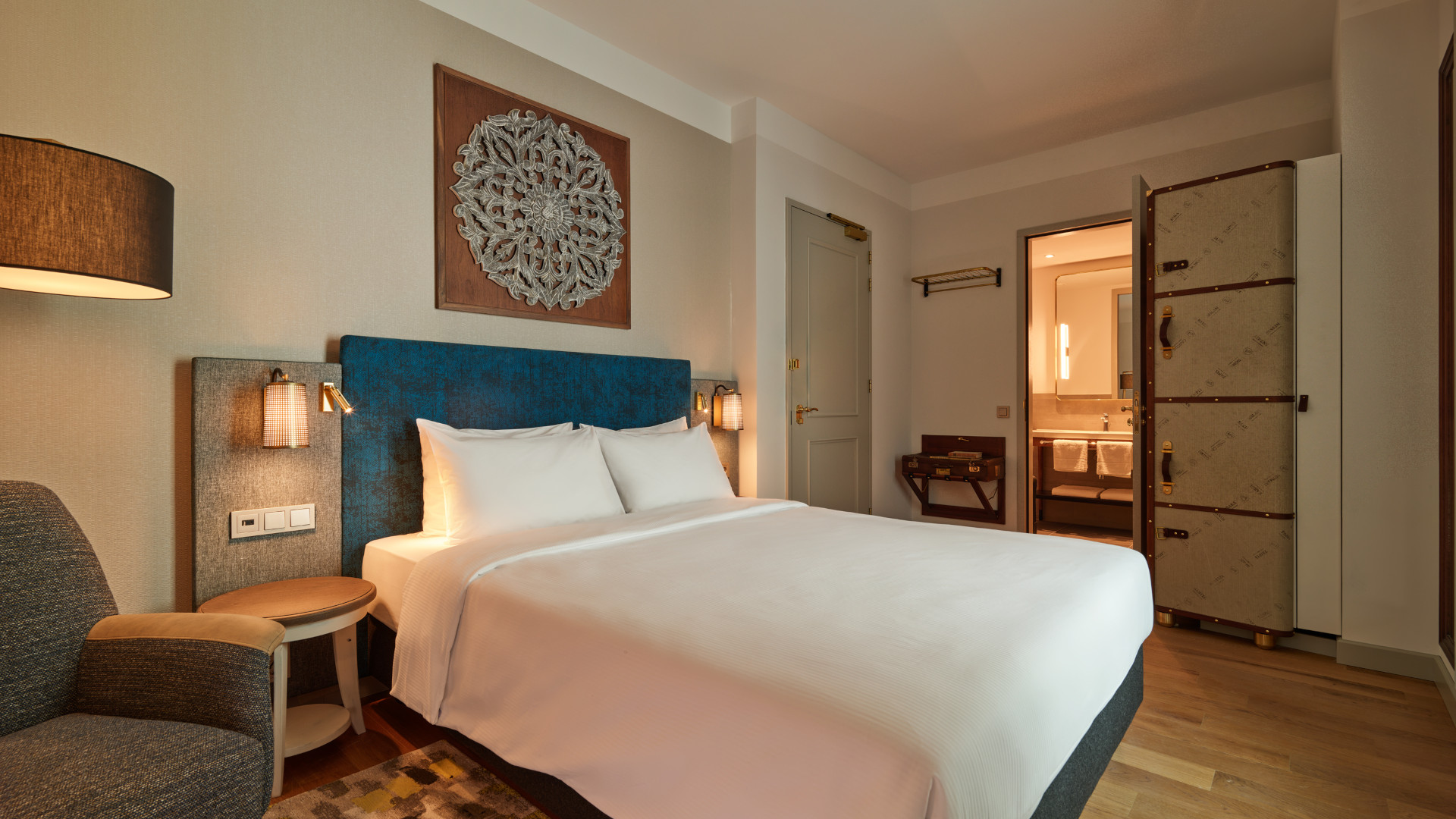 Modern guest room at voco The Hague with queen bed, coffee and tea facilities, and daylight atrium view.