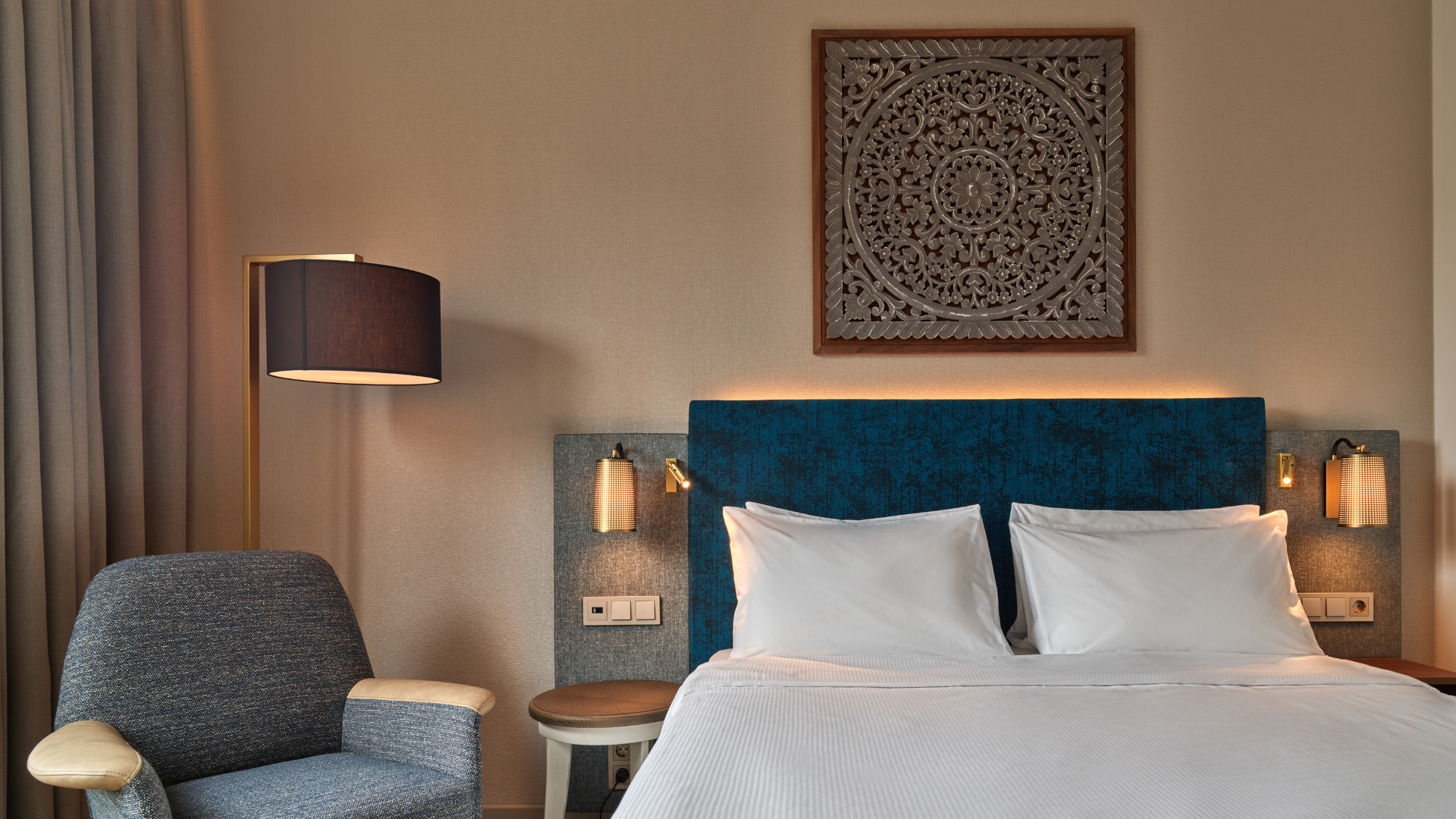 Elegant queen-size bed and artistic headboard in voco The Hague Atrium Room