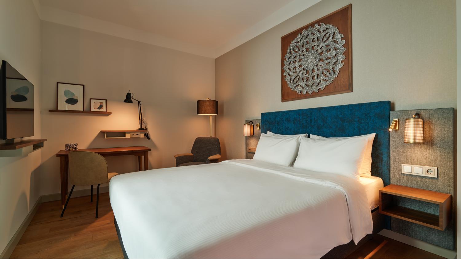 Comfortable Queen Bed Standard Room with warm lighting at voco The Hague