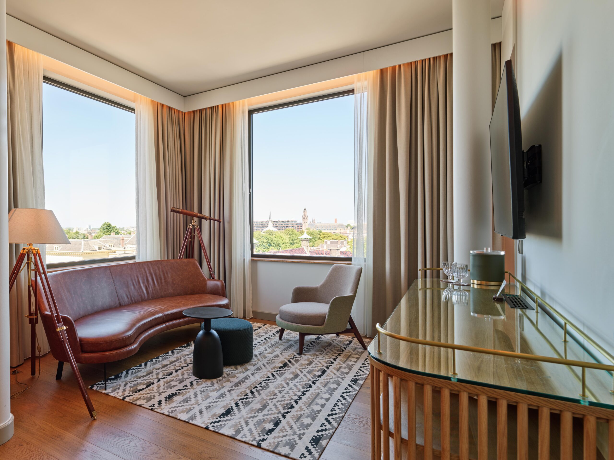 Lounge corner with armchair and city view from high‑floor King Suite – voco The Hague