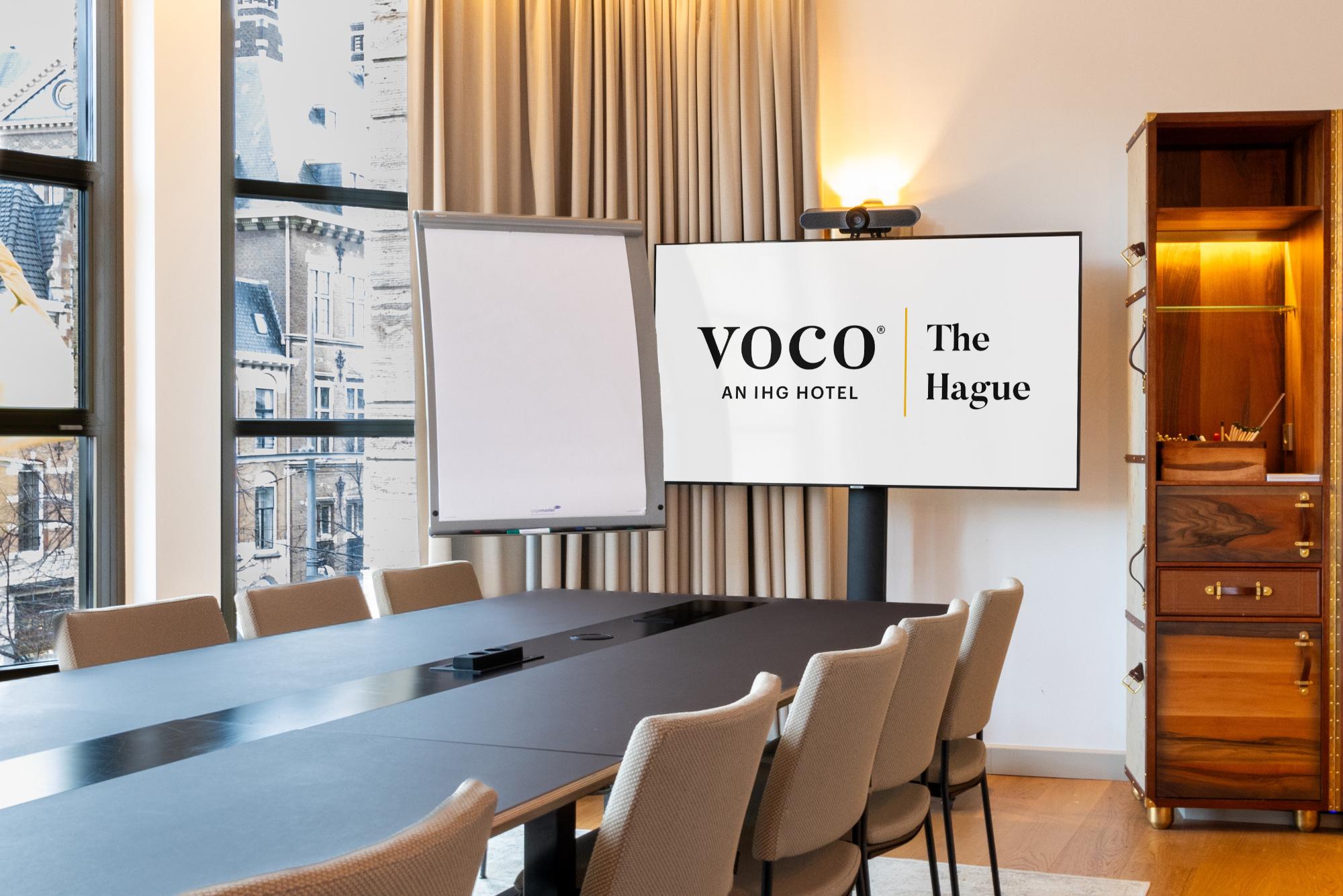 Private meeting room with video conferencing screen and bespoke furniture at voco The Hague