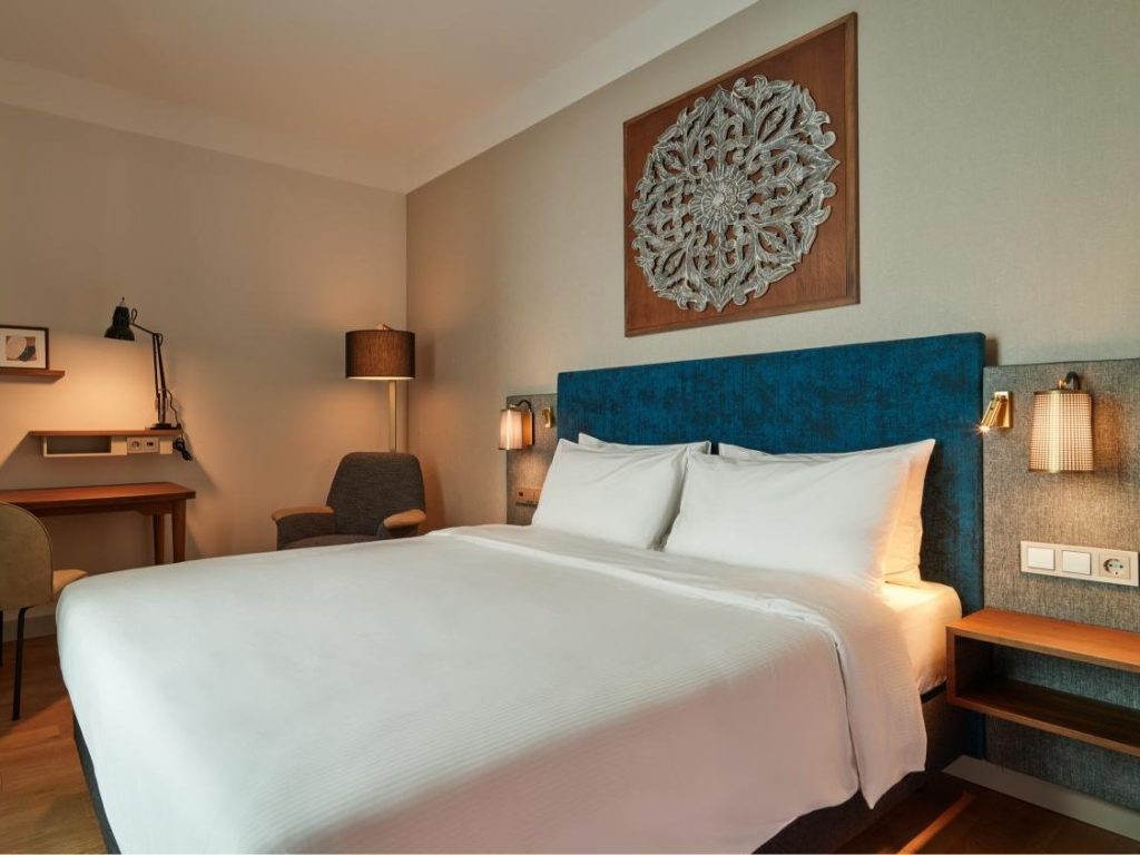 Comfortable Queen Bed Standard Room with warm lighting at voco The Hague